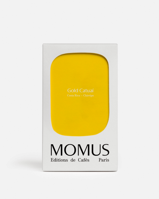 Packaging du café Gold Catuaí de Momus, éditions de cafés, avec façade jaune minimaliste.