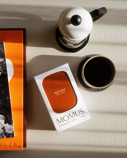 Packaging café Momus Éditions de Cafés Paris, variété Red Catuai du Brésil, présenté avec service à café et livre d'art en lumière naturelle