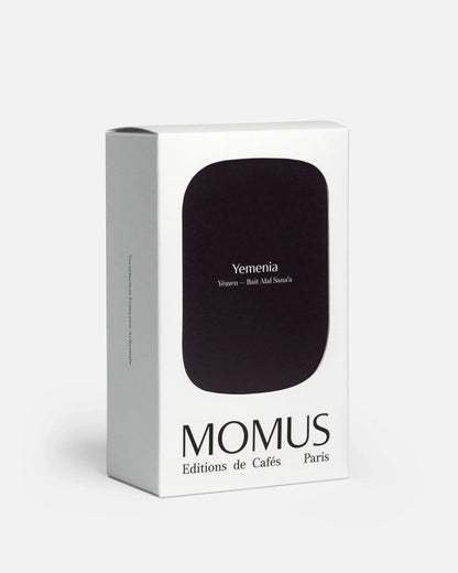 Packaging 200g du café Momus Yemenia - Yémen, Bait Alal Sana'a. La boîte présente une grande forme noir profond. Torréfaction Française Artisanale. Café rare du Yémen, connu pour ses notes fruitées et épicées.