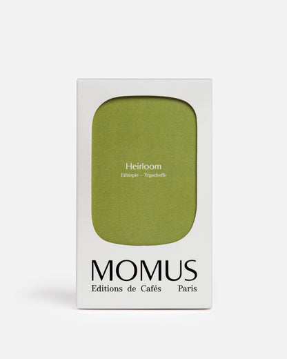 Packaging blanc du café Momus Heirloom Éthiopie - Yrgacheffe. La boîte présente une grande forme vert olive/vert kaki et le texte indique « Heirloom Éthiopie – Yrgacheffe ». Ce café, issu de l'agriculture naturelle et responsable, est idéal pour les méthodes filtres ou un espresso léger, révélant des notes florales et fruitées.