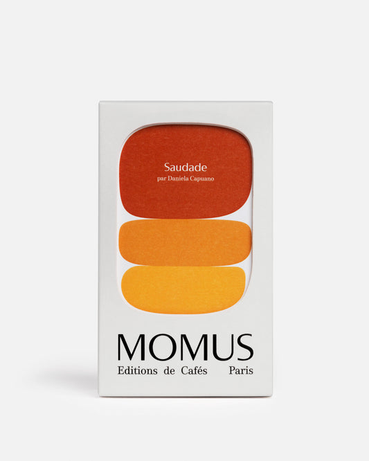 Saudade - Packaging du Café Espresso Doux Floral du Brésil de Momus. Boîte blanche avec les couleurs brun-rouge, orange et jaune représentant cet assemblage harmonieux sans amertume aux notes soyeuses. Création spéciale par Daniela Capuano, MOF.