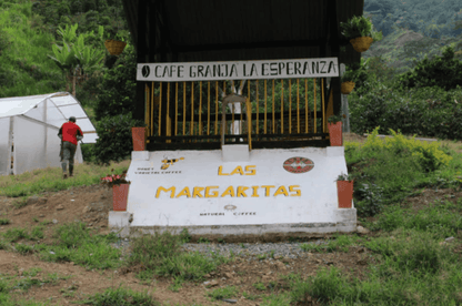 Entrée de la ferme Granja La Esperanza avec panneau "LAS MARGARITAS" et décor de plantes café Sudam Rume