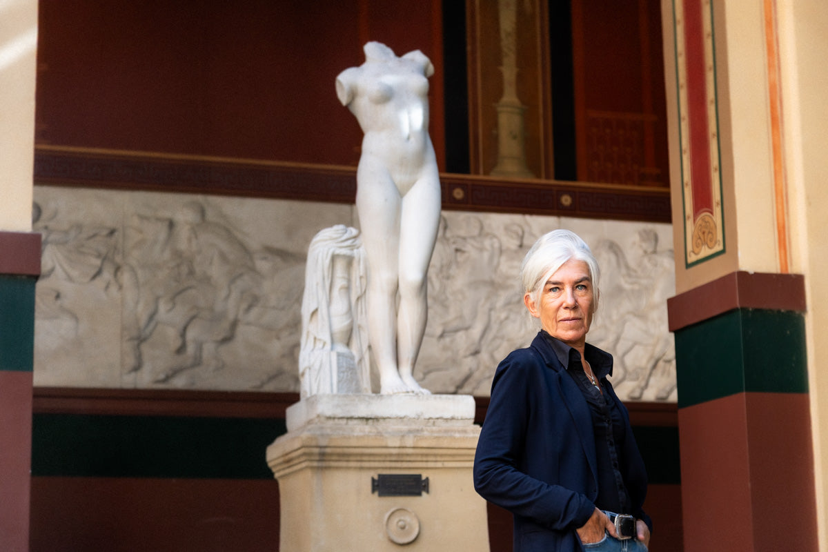 Nathalie Talec à côté d'une statue sans bras à l'intérieur d'une galerie des beaux arts