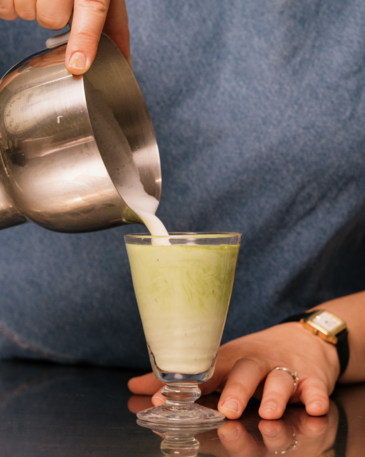 Préparation matcha latte avec lait moussé versé au pichet inox